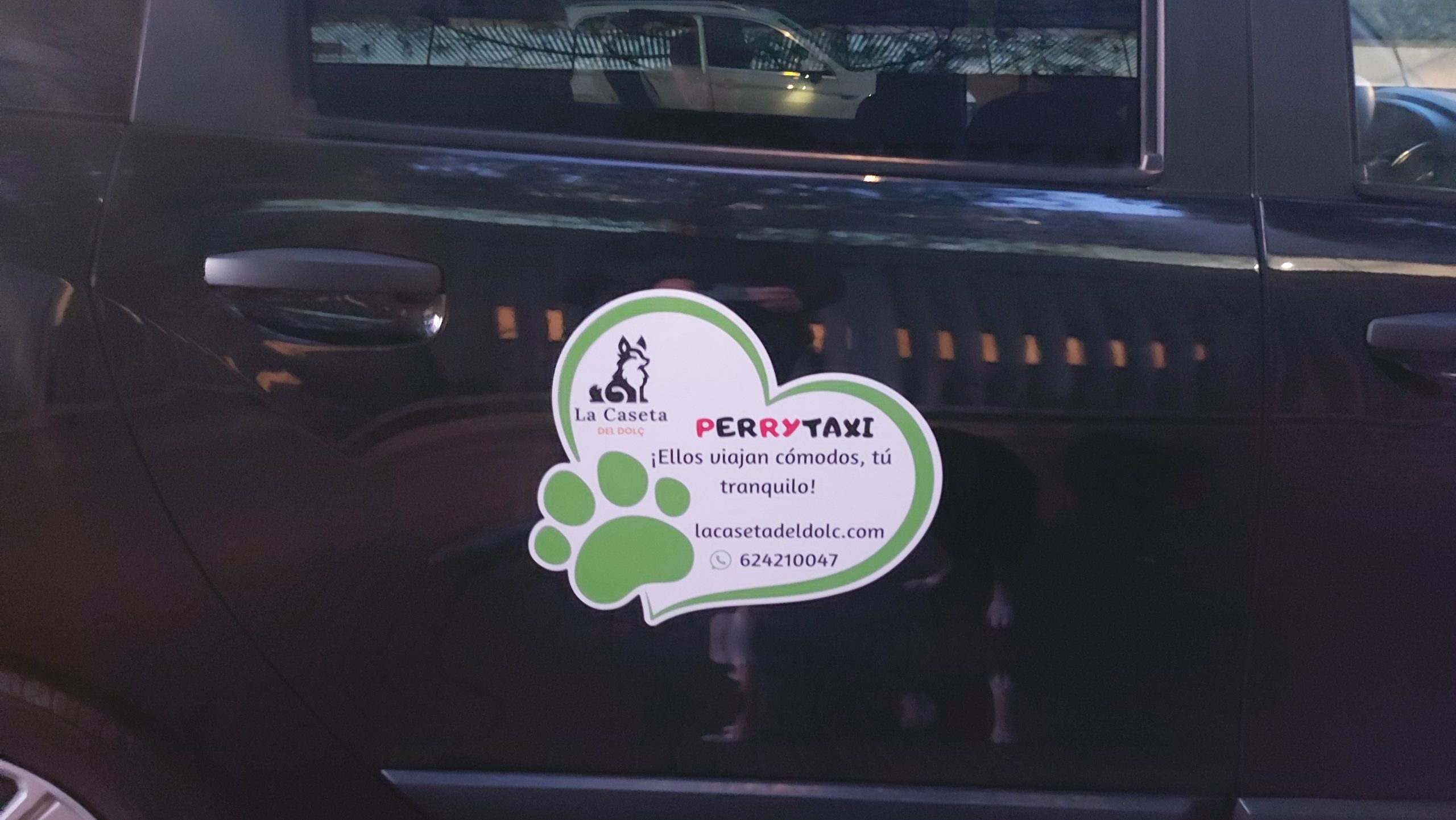 Pegatina en la puerta de un coche negro que promociona el servicio PerryTaxi de La Caseta del Dolç, con un diseño en forma de huella y corazón